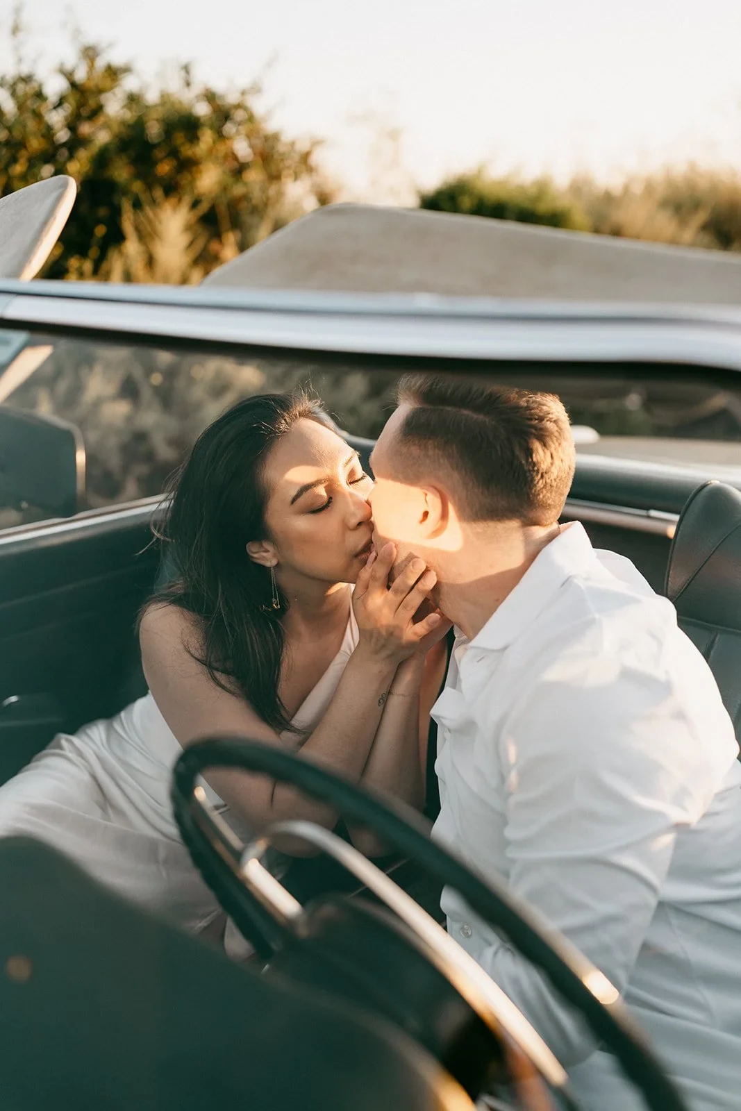 Pareja celebrando en un auto al atardecer